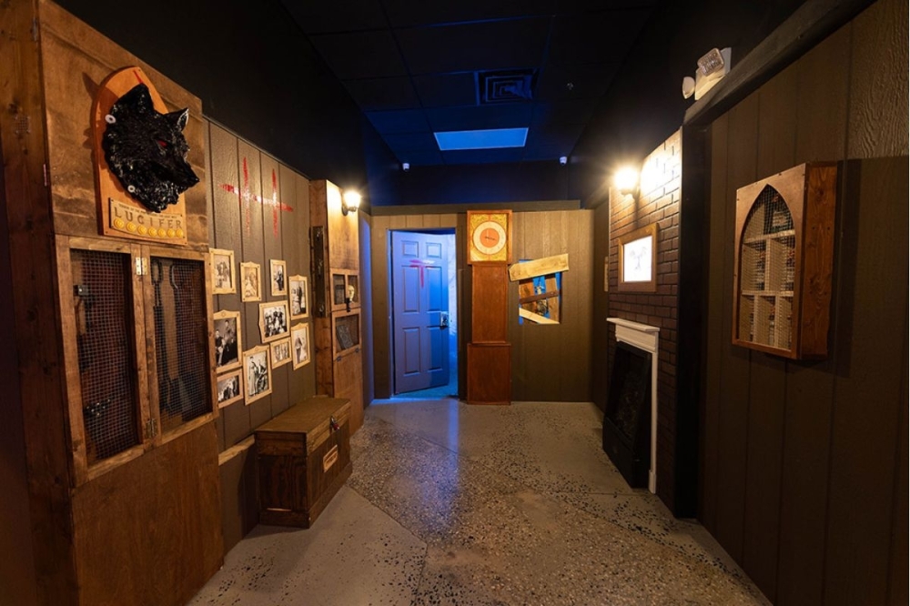 The challenge in themed puzzle space Room 172 involves escaping a haunted hotel room before being trapped inside forever. The room is dimly lit with spooky elements. (Courtesy Exit 4 Escape Rooms of Katy)